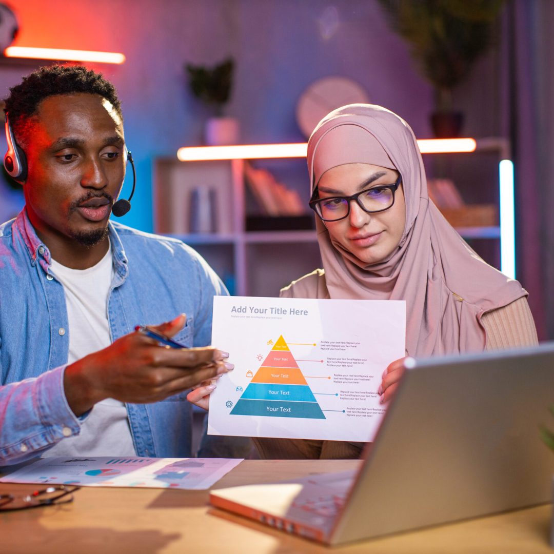 Black man and arabian woman sitting at home office and using modern laptop for video call. Two mixed race colleagues having working meeting online. Concept of people and cooperation.